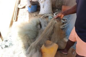 Leon Kisito Bekwale holding the oil net duped at the corner of his house